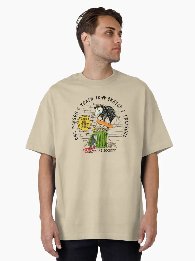 A natural beige cotton t-shirt with a vintage-style print of an opossum on a skateboard, celebrating the "Street Cat Society" subculture.