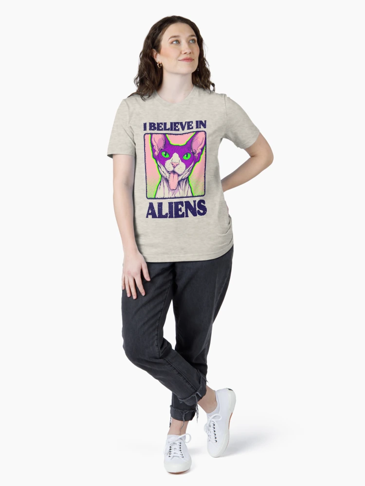 Woman wearing a casual light grey t-shirt with a centered 'I Believe in Aliens' hairless cat design.