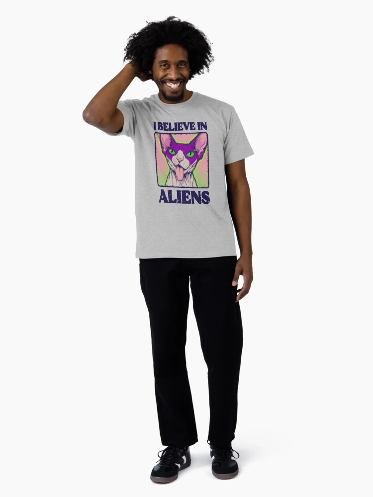Close-up of a man in a heather grey t-shirt featuring a stylized extraterrestrial feline graphic on the chest.